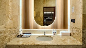 A bathroom with a large oval mirror, a sink, and a vanity. - Marine Bay Sanur (Denpasar)