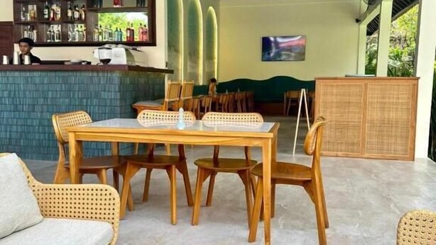 A restaurant with a bar area, wooden furniture, and a large round wooden table. - Marine Bay Sanur (Denpasar)