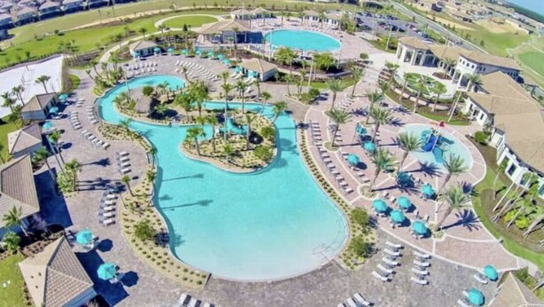 An aerial view of a resort with multiple swimming pools, sun loungers, and palm trees. - Disney 8BR Villa, Pool + Hot Tub, Theater, Game Room, Themed Bedroom, Sleeps 16+ (Four Corners)