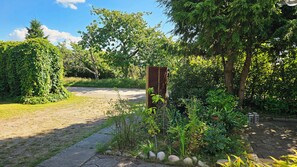 Un jardín con un sendero pavimentado, una cerca de madera y diversas plantas.