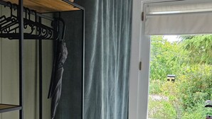 Una habitación con literas, una cortina gris, una cesta de mimbre y vistas a zonas verdes.