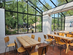 A restaurant with large windows, wooden tables, and chairs.