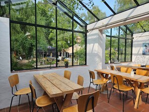 Ein Restaurant mit großen Fenstern, Holztischen und -stühlen.
