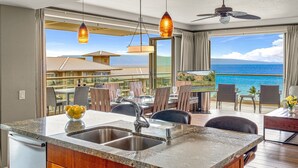 A kitchen with a sink, wooden cabinets, and a view of the ocean.