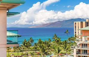 A resort with a view of the ocean and mountains, featuring palm trees and a pool area. - Maui Resort Rentals: Honua Kai - Upgraded 8th Floor 3BR Pairing, Stunning Ocean & Mountain Views plus Wrap-Around Balcony! (Lahaina)