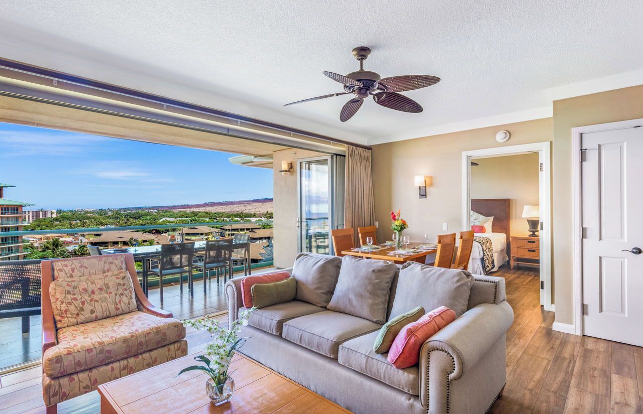 A spacious balcony with a dining area, a sofa, and a ceiling fan.