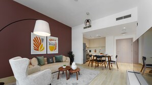 A modern living room with a sofa, armchair, coffee table, and artwork on the wall. - Maison Privee - Exquisite Apt on Yas Island cls to ALL attractions (Abu Dhabi)