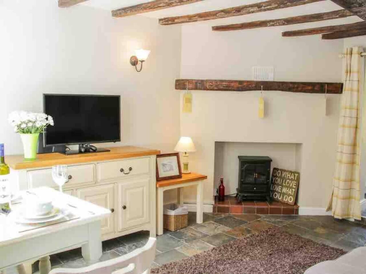 A cozy living room with a fireplace, a television, and a dining area with a table set for two.