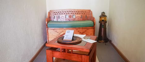 A small room with a wooden bench, a table with a sign, and a lamp.