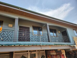 A two-story building with a balcony, storefronts, and signage. - Lovely & Cute Condo - Close to Highway - Parking (Accra)
