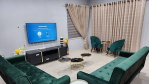 A modern living room with green sofas, a TV, and a console table. - Spacious Luxury 3Bed Hse in Tema - Netflix, Wi-fi (Tema)