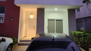 A modern two-story building with a flat roof, a white door, and a garage door. - Spacious Luxury 3Bed Hse in Tema - Netflix, Wi-fi (Tema)