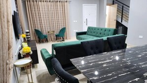 A modern living room with a green sofa, a black tufted sofa, a marble dining table, and a small side table. - Spacious Luxury 3Bed Hse in Tema - Netflix, Wi-fi (Tema)