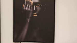 Una obra de arte enmarco con fondo oscuro y una mano que se extiende hacia el espectador.