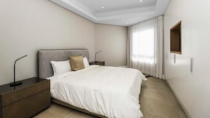 Ein modernes Hotelzimmer mit einem großen Bett, einem Nachttisch, einer Lampe und einem Spiegel an der Wand.