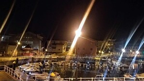 Vista nocturna d'una zona portuària amb un moll i embarcacions.
