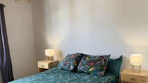 Ein Schlafzimmer mit einem Bett, zwei Nachttischen, einer Hängeleuchte und einer Holzbalkendecke.
