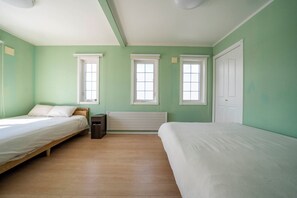 A room with two single beds, a radiator, and two windows. - THE GARNET HIGASHIKAWA (Higashikawa)
