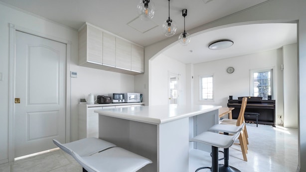 A modern kitchen with white cabinetry, a central island with bar stools, and pendant lighting. - THE GARNET HIGASHIKAWA (Higashikawa)