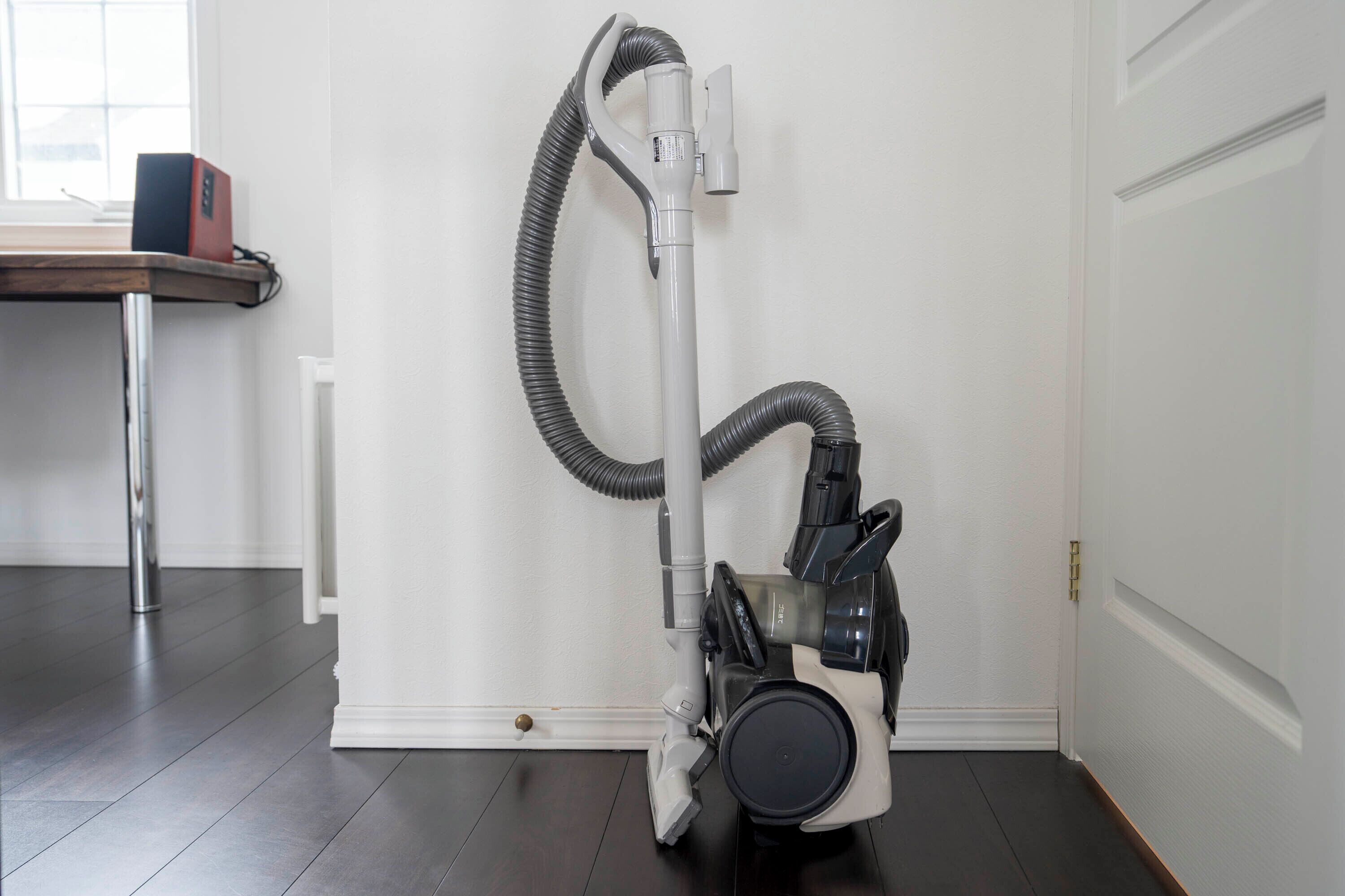 Un aspirador en una habitación con piso de madera y una puerta blanca.