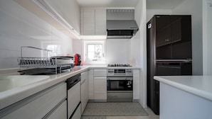 A modern kitchen with white cabinetry, a gas stove, an oven, and a black refrigerator. - THE GARNET HIGASHIKAWA (Higashikawa)