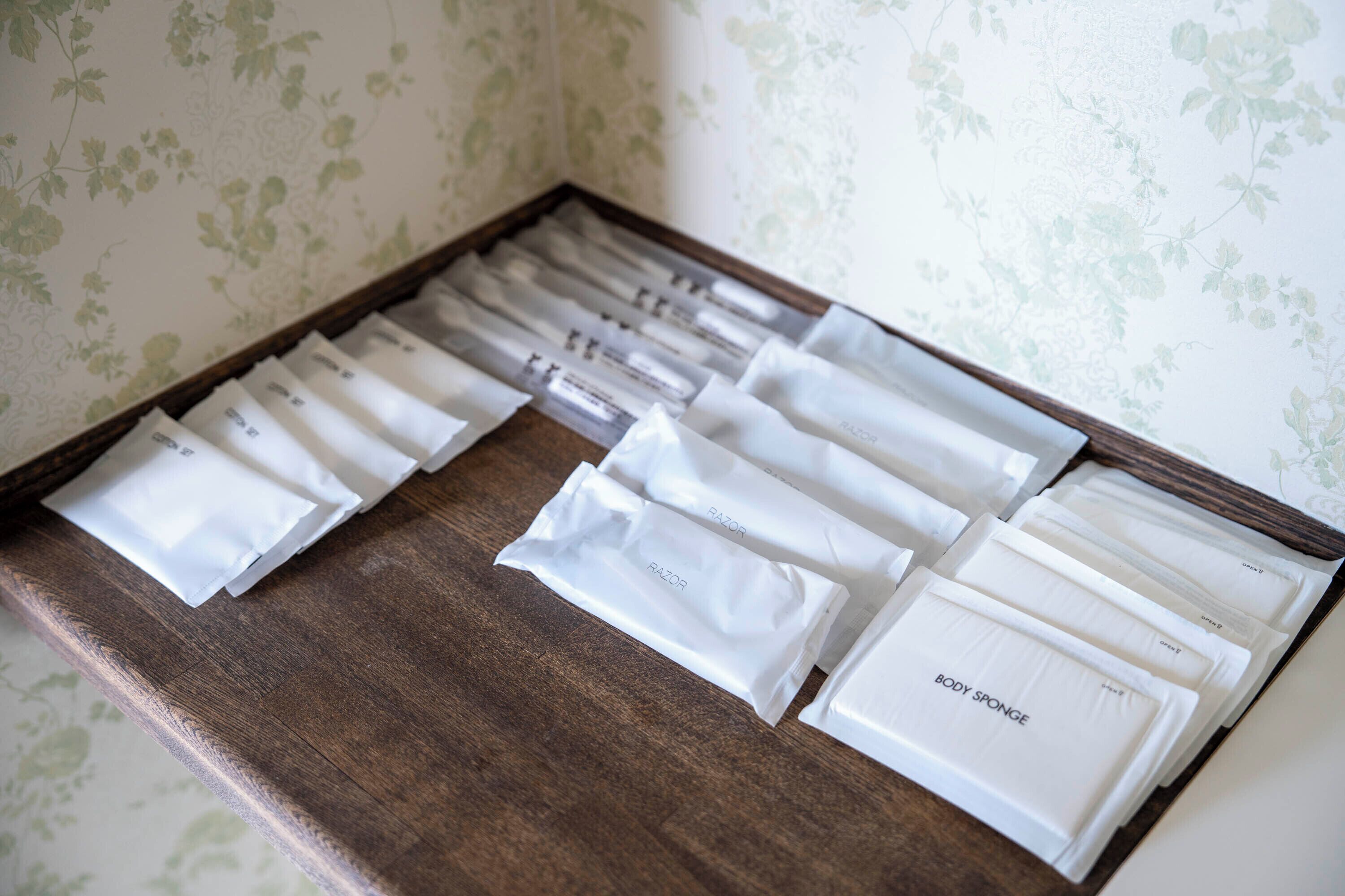 Un plateau en bois contenant des articles de toilette soigneusement disposés, notamment des rasoirs et une éponge pour le corps.