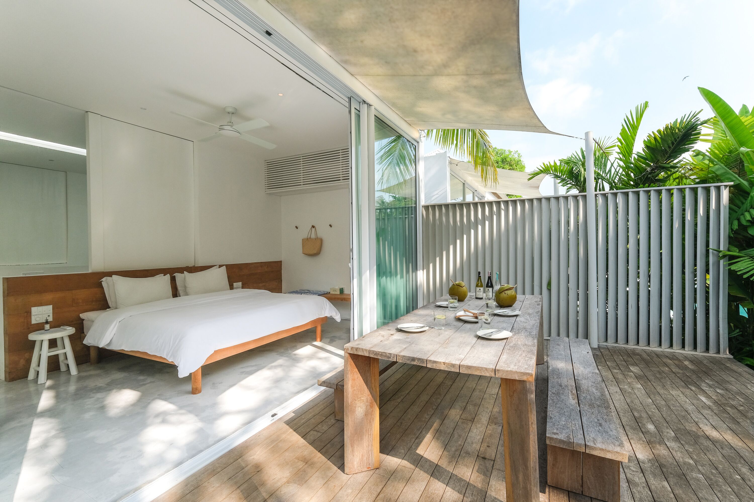 A bedroom with a bed, bedside table, and a window overlooking a garden.