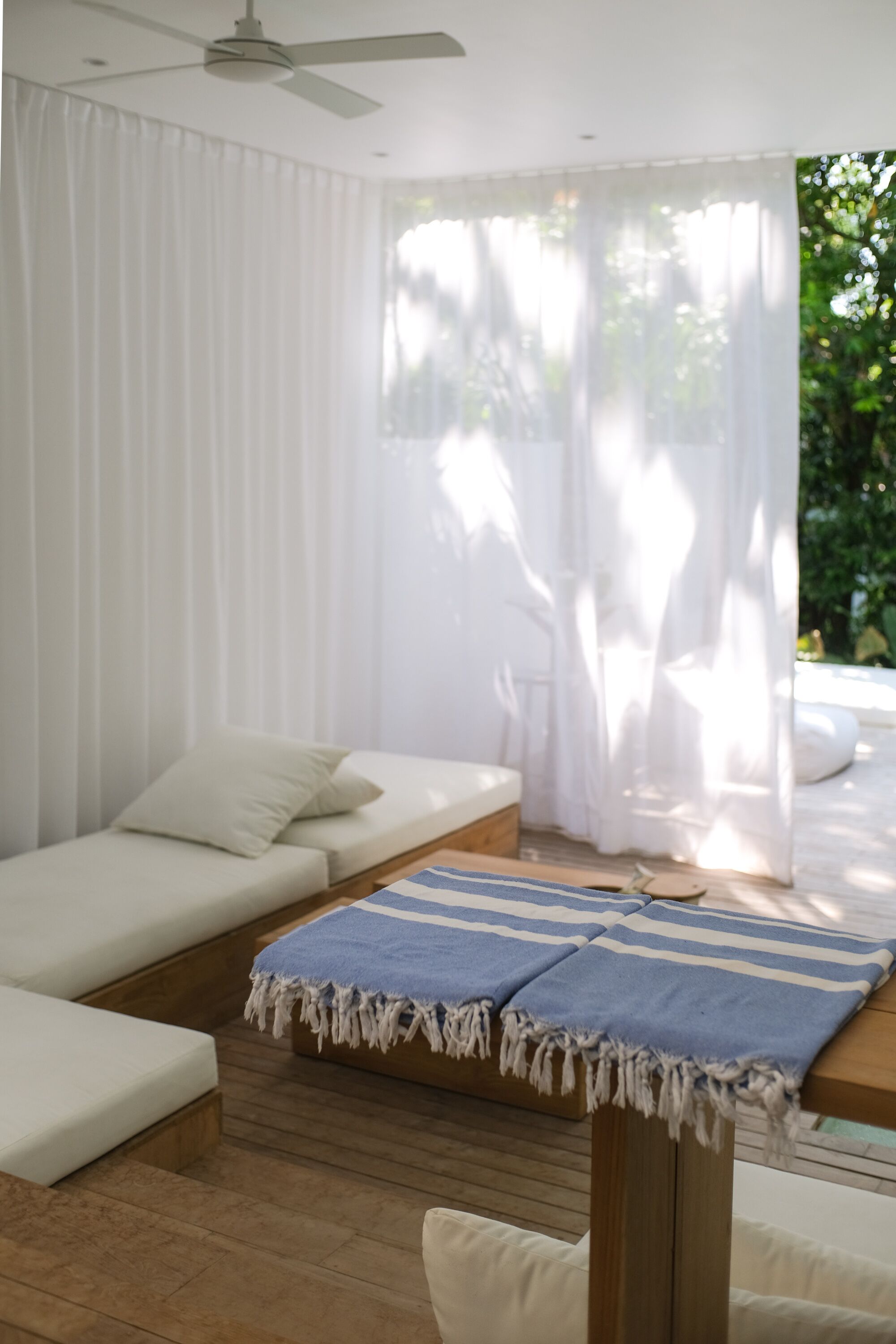 Ein modernes Zimmer mit einer Couch, einem Holztisch und leicht transparenten Vorhängen, die natürliches Licht hereinlassen.