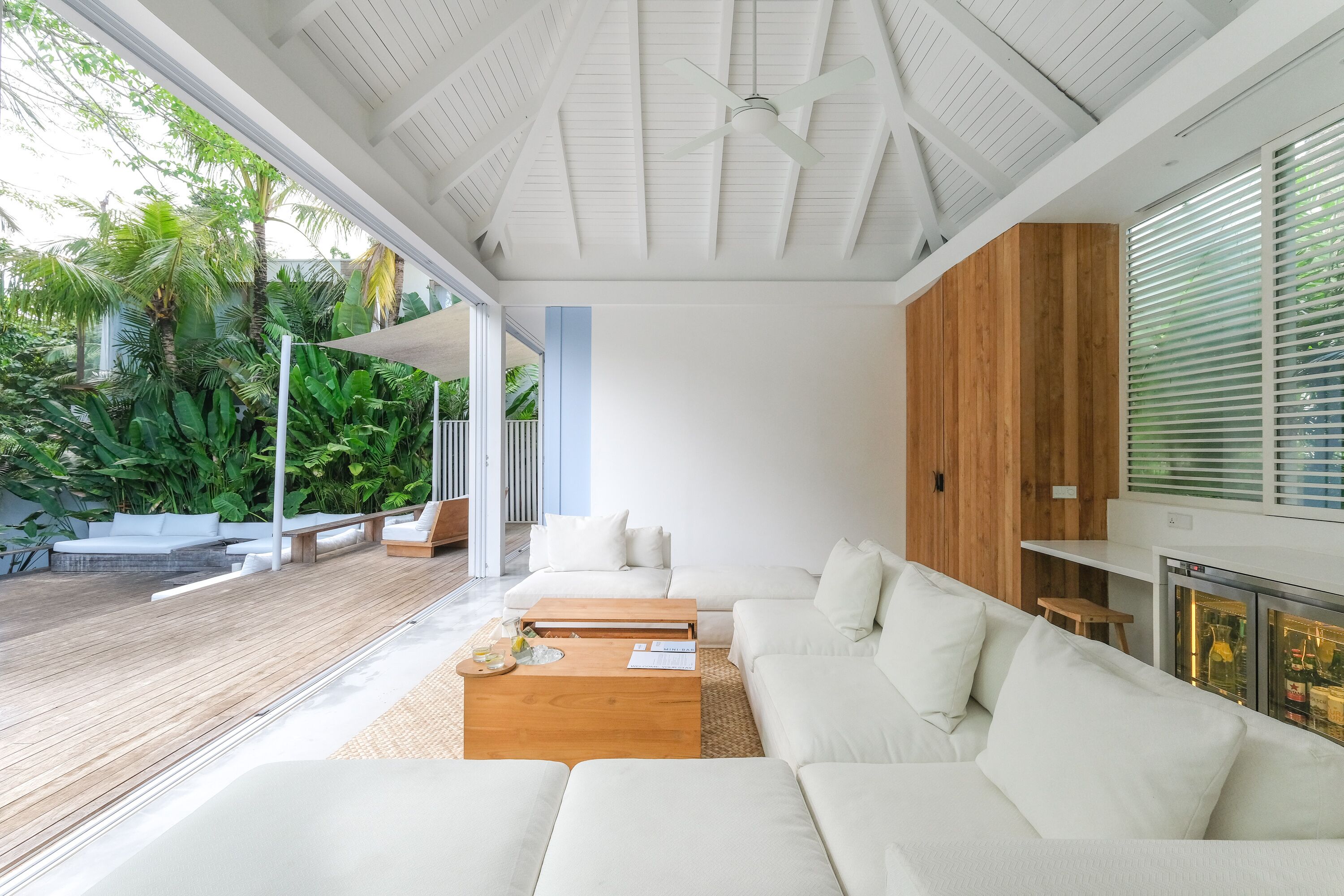 A modern living room with a white sofa, a wooden coffee table, and a ceiling fan.