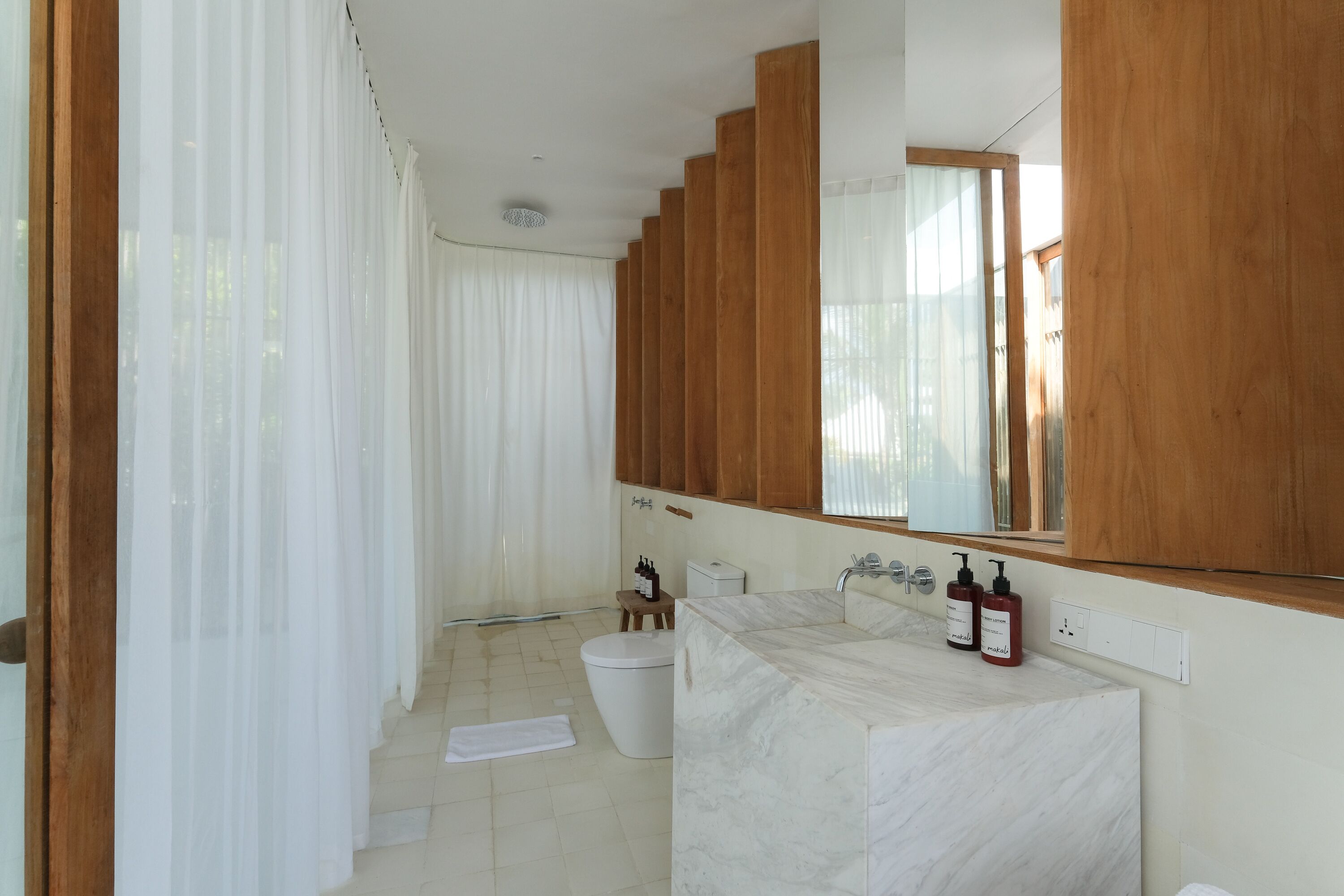 A modern bathroom with a marble sink, wooden cabinets, and a large mirror.