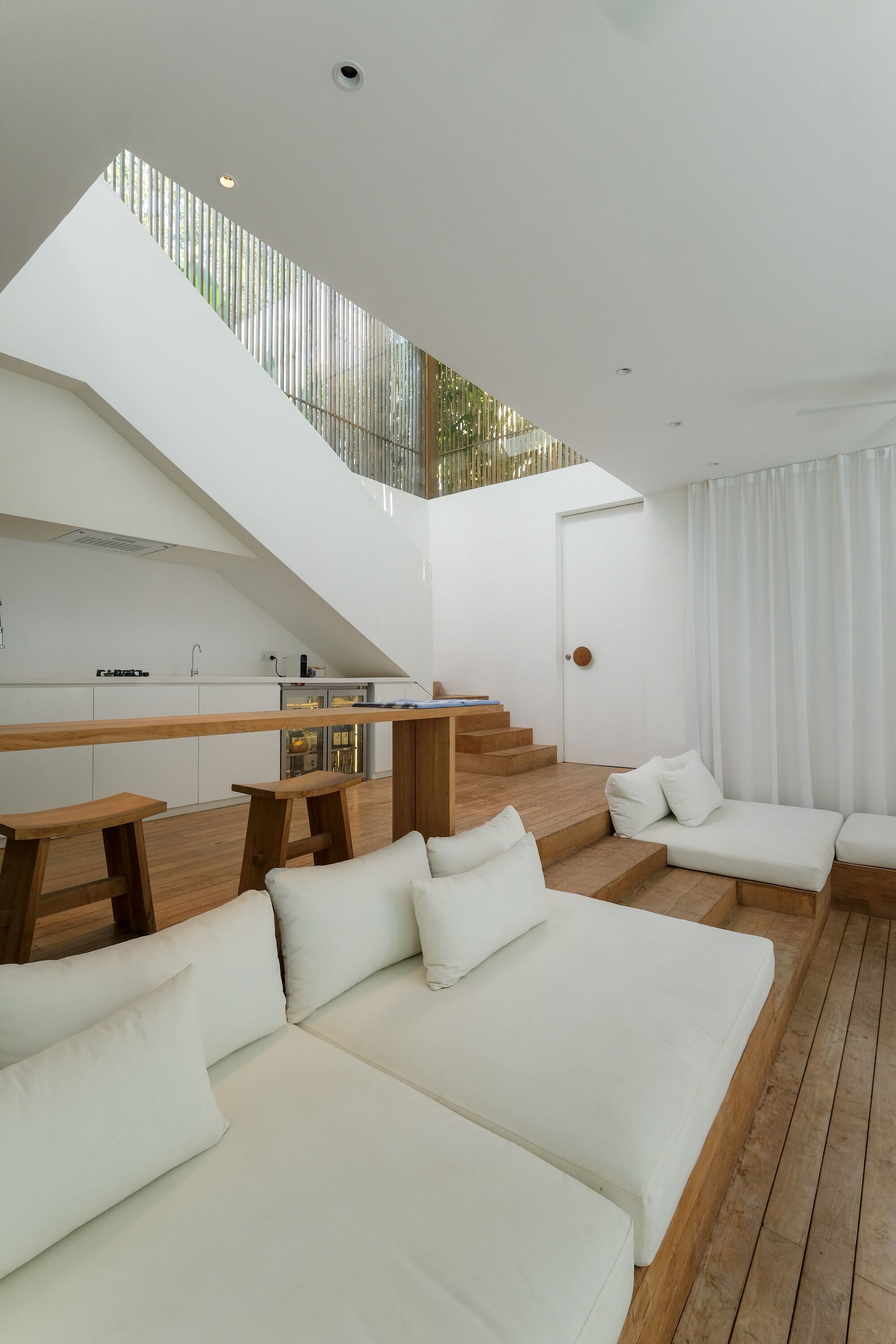 A modern interior with a kitchen, a staircase, and a seating area.