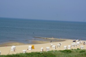 Een strand met rijen met parasols en een paar mensen in het water.