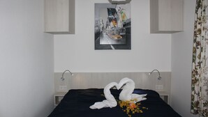 A hotel room with a bed, a wall-mounted painting, a light fixture, and a floral curtain. - Ferienwohnung mit Maritimer Ausstattung, Seeblick und Schwimmbad - Haus Seehund (Cuxhaven)