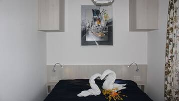 Ein Hotelzimmer mit Bett, Wandbild, Leuchte und einem blumigen Vorhang.