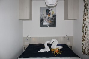 Een hotelkamer met een bed, een aan de muur hangend schilderij, een lamp en een bloemen gordijn.