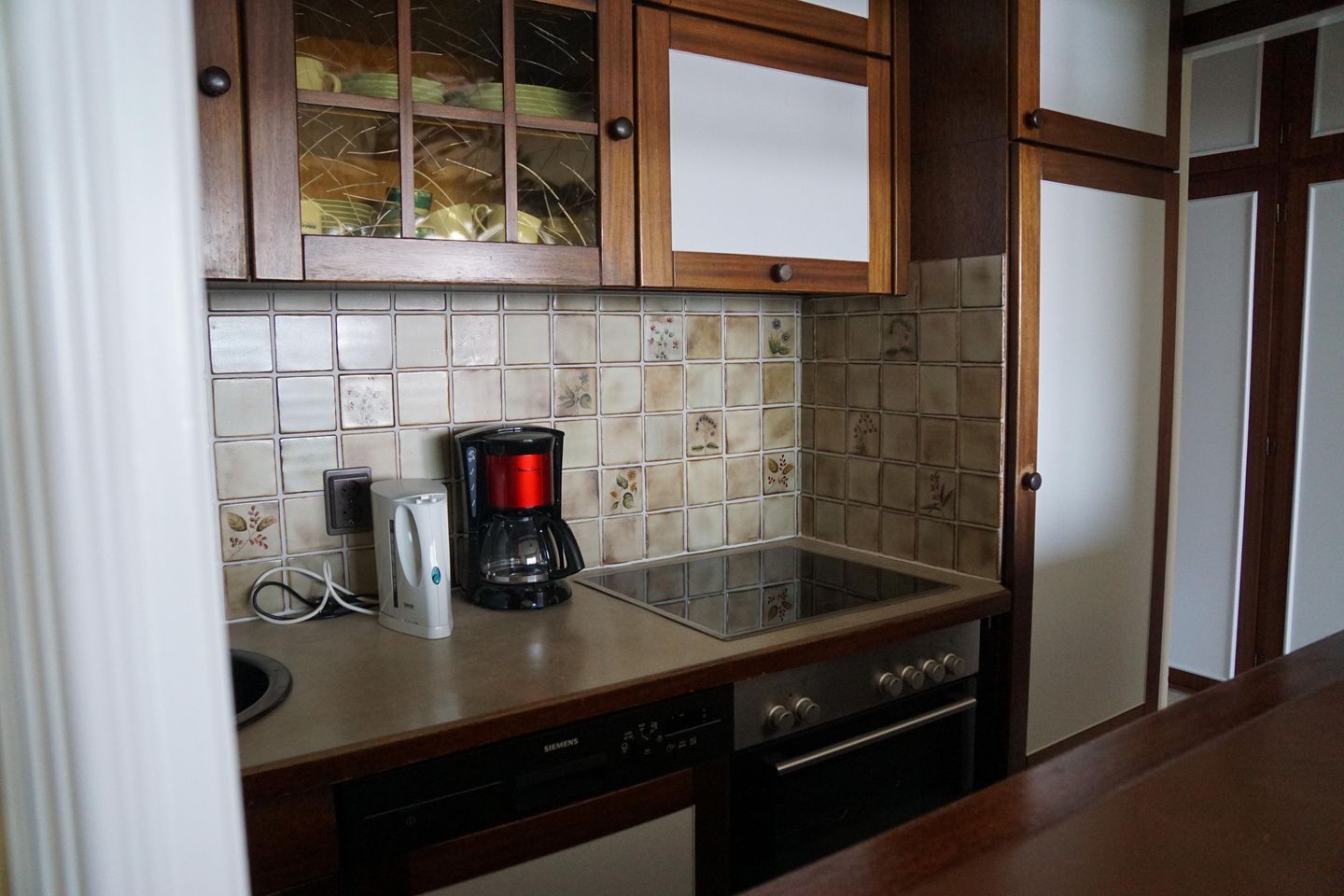 A kitchen with wooden cabinets, a tiled backsplash, a coffee maker, a dishwasher, and an oven.