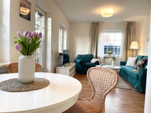 Een woonkamer met een ronde tafel, een bank, een tv-meubel en een stoel.