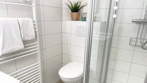 A modern bathroom with a toilet, shower, and a glass-enclosed shower area.