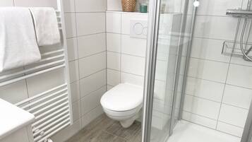 A modern bathroom with a toilet, shower, and a glass-enclosed shower area.