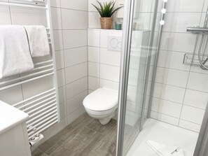 A modern bathroom with a toilet, shower, and a glass-enclosed shower area.