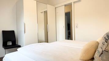 A bedroom with a bed, a wardrobe, a chair, and a mirror.