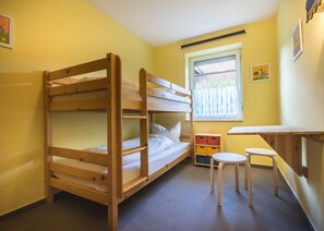Dormitorio con literas, ventana, una mesita y una silla.