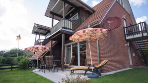 A two-story building with a balcony, outdoor seating with umbrellas, and a satellite dish.