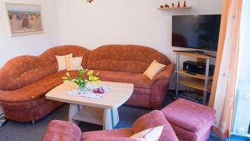 Ein Wohnzimmer mit einer Couch, einem Couchtisch und einem Fernseher.
