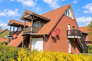 Un bâtiment à deux étages, doté d’un toit recouvert de tuiles rouges, d’un balcon et d’un escalier.