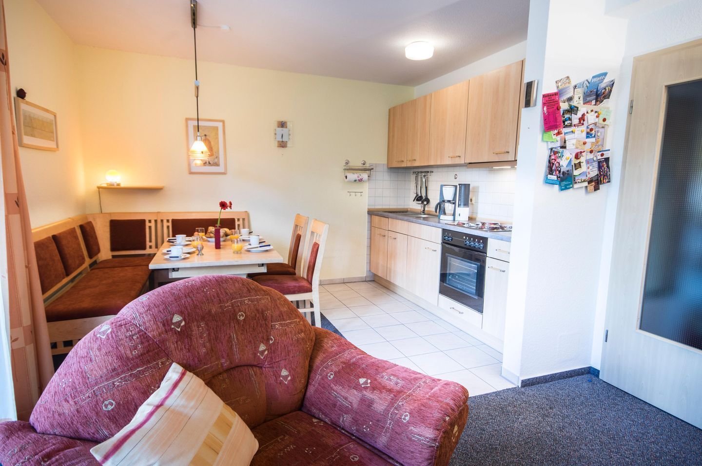 Un espace de vie compact comprenant un coin repas, une kitchenette et un canapé avec un coussin.
