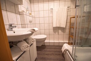 Un baño con lavamanos, inodoro y zona de ducha.