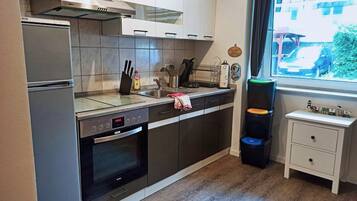 Una cocina con horno integrado, un lavabo y una ventana con vista a la calle.