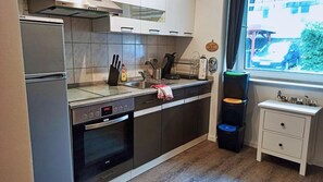 Una cocina con horno integrado, un lavabo y una ventana con vista a la calle.