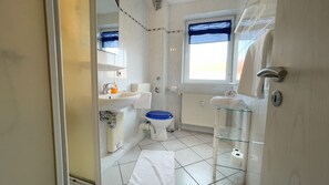 Une salle de bain équipée de toilettes, d’un lavabo et d’une douche à parois en verre.